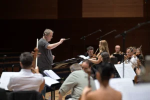 Dyrygent Wojciech Czepiel podczas prowadzenia próby orkiestry symfonicznej.